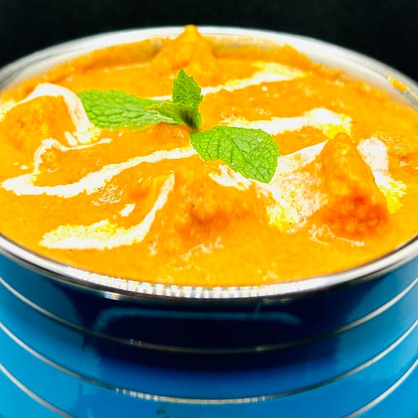 Himalayan Spice Indian Cuisine's creamy orange curry, garnished with fresh mint, in a blue bowl.