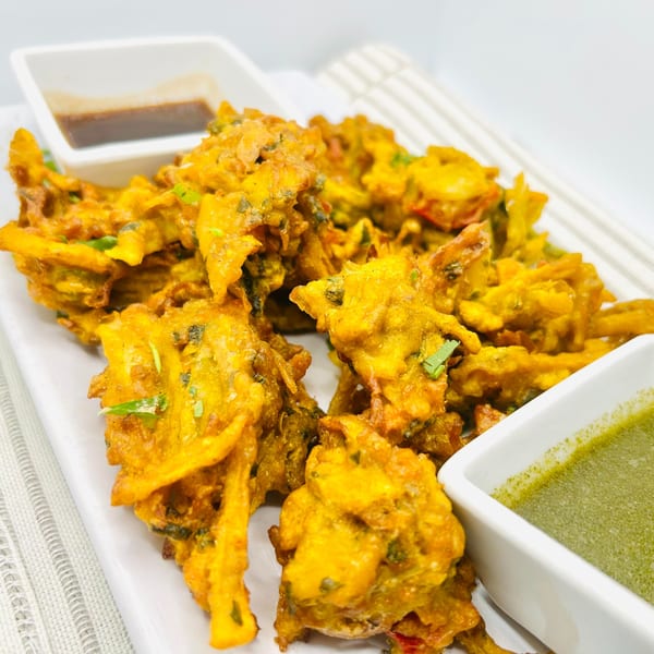 Himalayan Spice Indian Cuisine's golden-fried pakoras with two dipping sauces on a white plate.